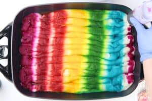 wool snaked in an electric skillet with stripes of dye in a rainbow pattern