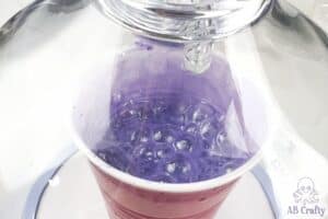 a solo cup with purple resin bubbling up within the let's resin bubble remover machine