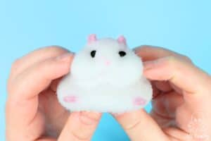 holding a diy taba squishy in the shape of a white hamster