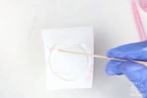 using a popsicle stick to pop bubbles on a mold filled with white silicone