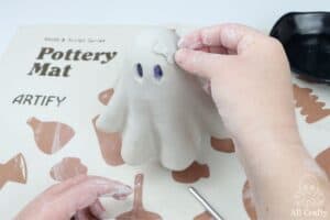 sticking the clay bow to the top of the ghost