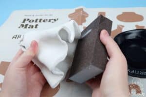 using a sanding black to sand the edges of the clay sculpture