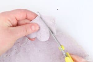 using scissors to cut a heart out of the seed paper