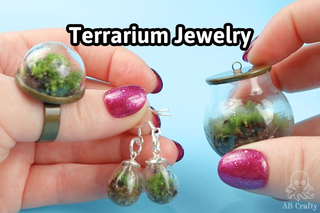 A complete handmade terrarium jewelry set with a text overlay that reads "Terrarium Jewelry" against a solid light blue background.